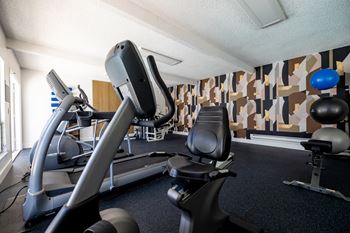 A gym with cardio equipment in a hotel gym room